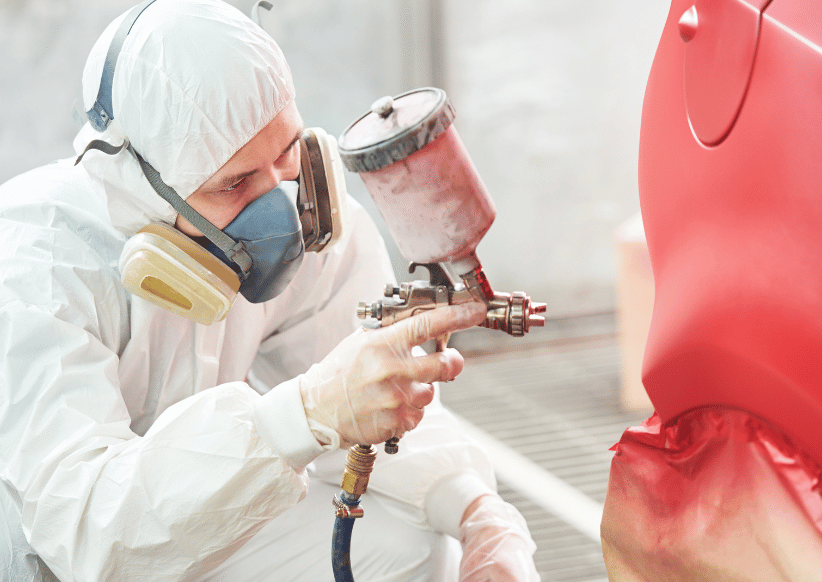 Technician performing automotive painting in Malden using a spray gun on a car