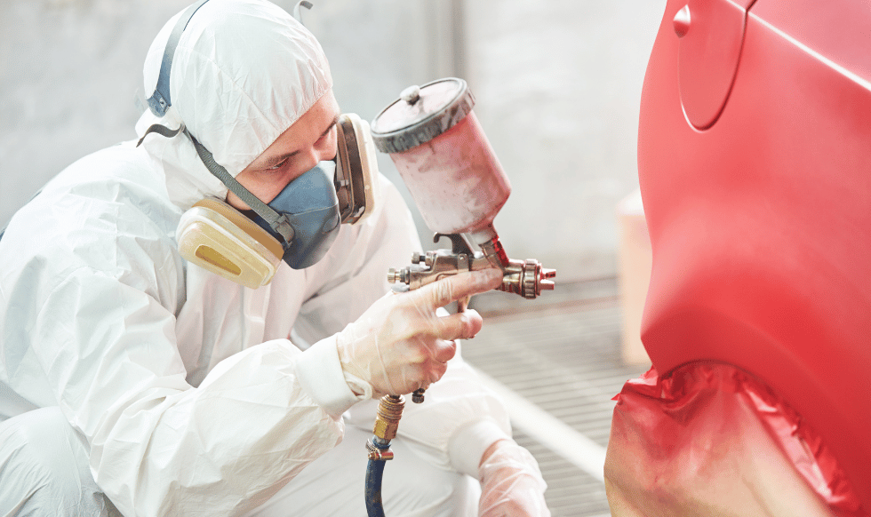 Technician performing automotive painting in Malden using a spray gun on a car